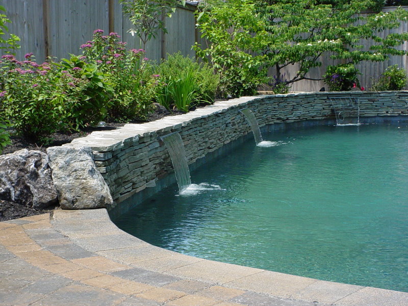 stacked stone waterfall into backyard pool